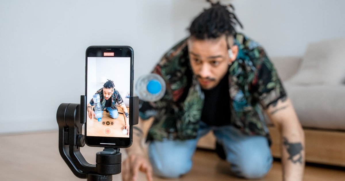 Créateur filmant une vidéo verticale au smartphone sur un trépied dans un studio lumineux
