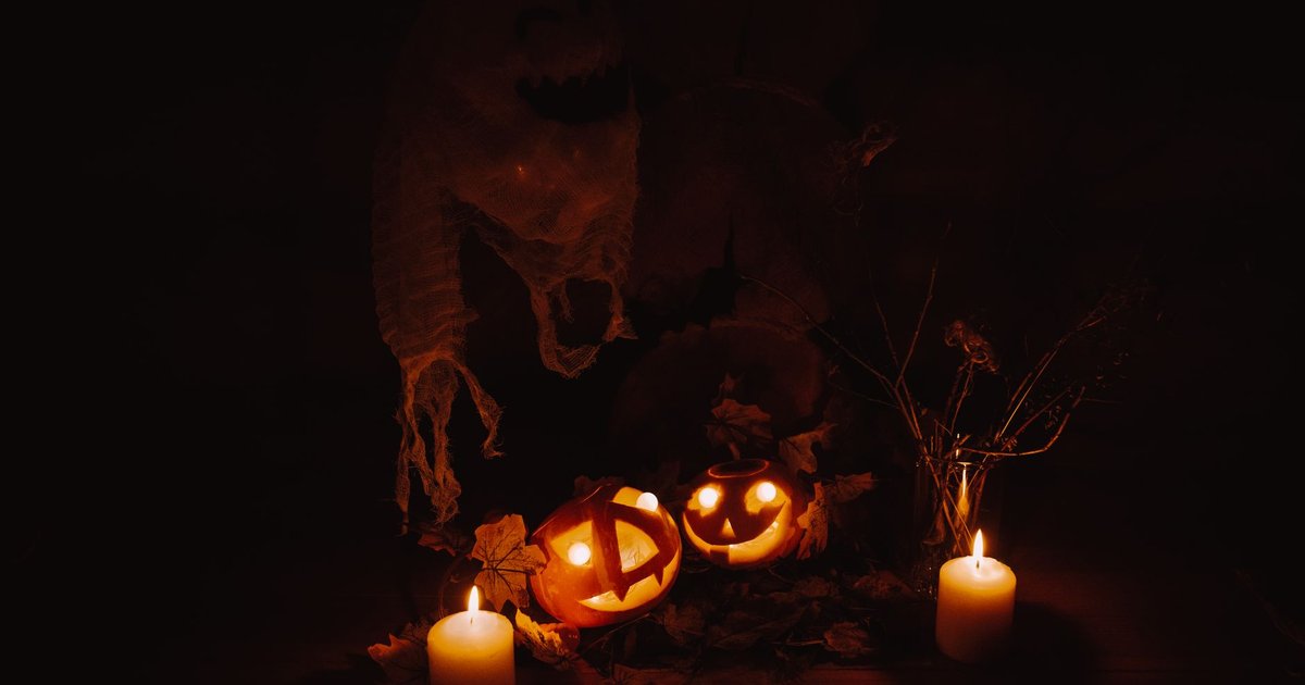 Citrouilles sculptées illuminées entre deux bougies dans un décor d'Halloween sombre