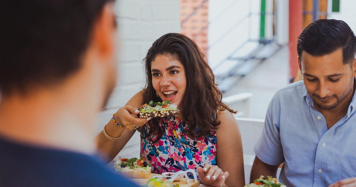 Trois amis partagent des tartines garnies à la terrasse d'un petit restaurant, en plein déjeuner