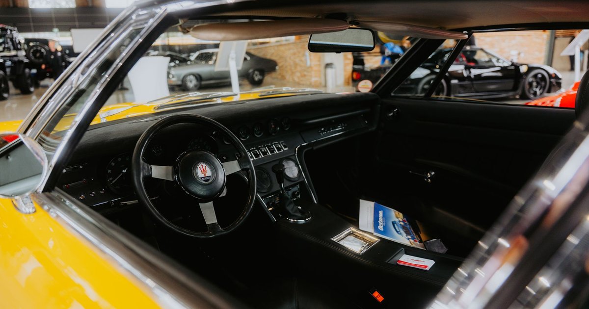 Habitacle d'une voiture de sport jaune exposée dans un salon automobile, d'autres modèles en arrière-plan