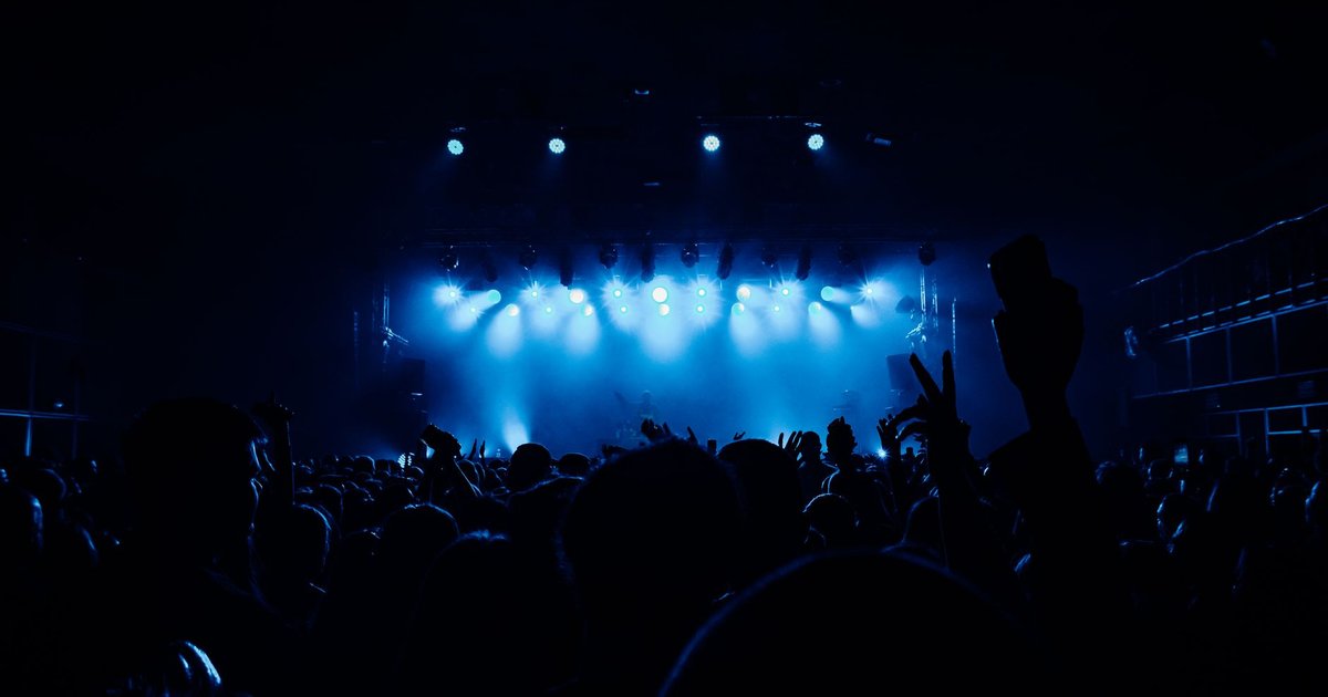 Foule de concert en silhouette devant une scène éclairée de projecteurs bleus