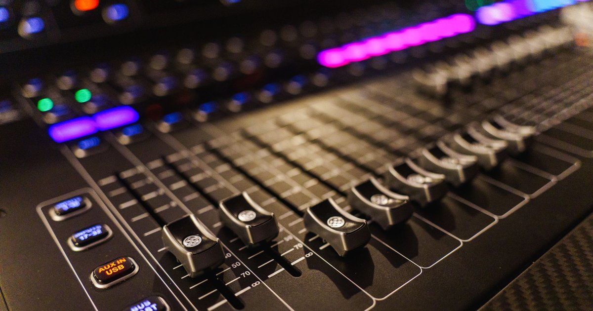 Vue rapprochée d’une console de mixage audio professionnelle éclairée dans un studio d’enregistrement