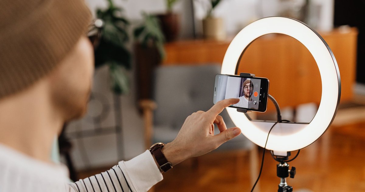 Créateur de contenu déclenchant l'enregistrement vidéo sur un smartphone monté devant un anneau lumineux
