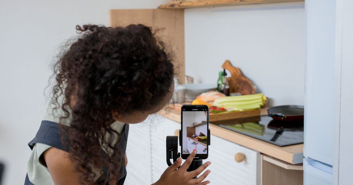 Une créatrice aux cheveux bouclés filme une vidéo de cuisine avec un smartphone monté sur stabilisateur