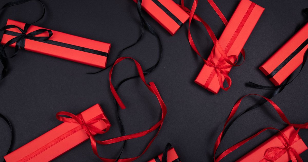 Coffrets cadeaux rouges noués de rubans noirs, disposés à plat sur un fond sombre