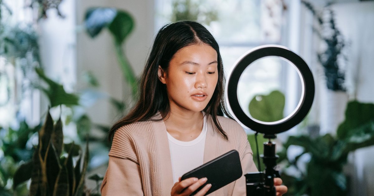 Créatrice réglant son téléphone sur un anneau lumineux avant un direct