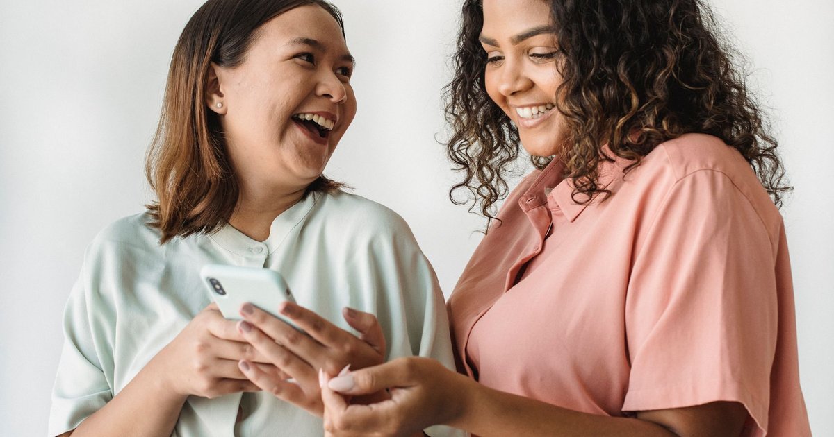 Deux personnes rient en regardant ensemble une vidéo sur un smartphone
