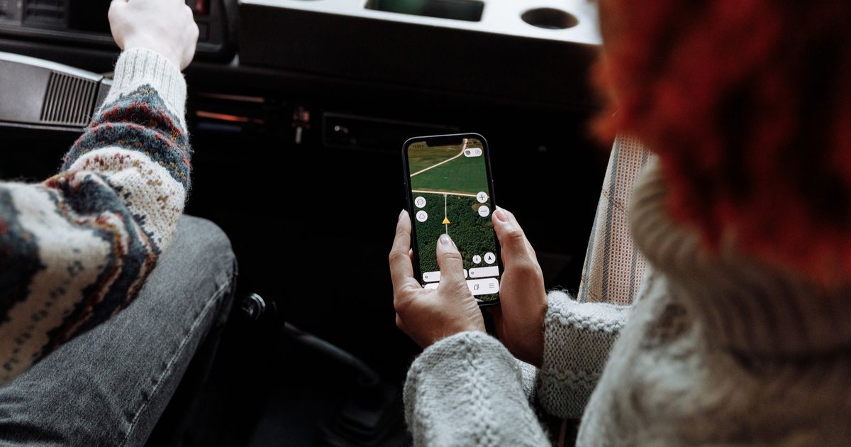 Voyageuse consultant son smartphone dans un aéroport, valise à la main