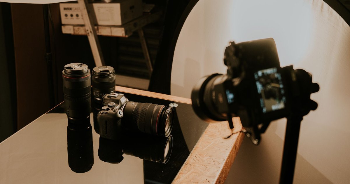 Boîtiers et objectifs photo posés sur une table de studio de tournage, éclairés par une boîte à lumière circulaire