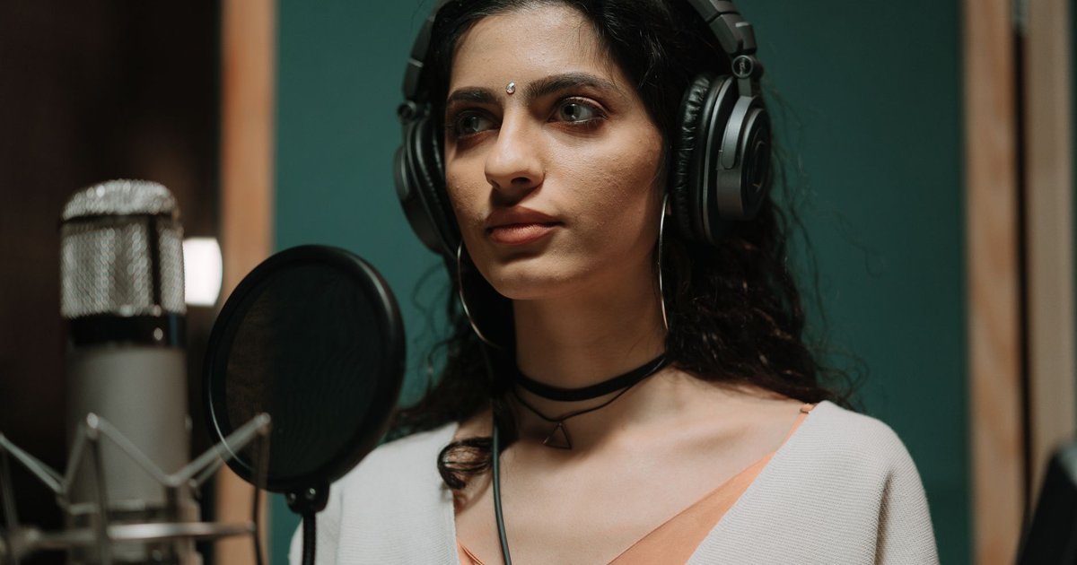 Chanteuse en séance d'enregistrement en studio, casque sur les oreilles, devant un micro à suspension