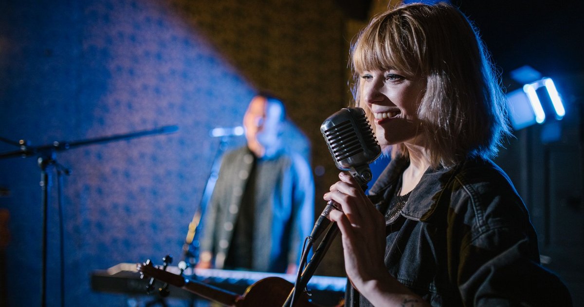 Chanteuse au micro sur une scène de concert éclairée par des projecteurs