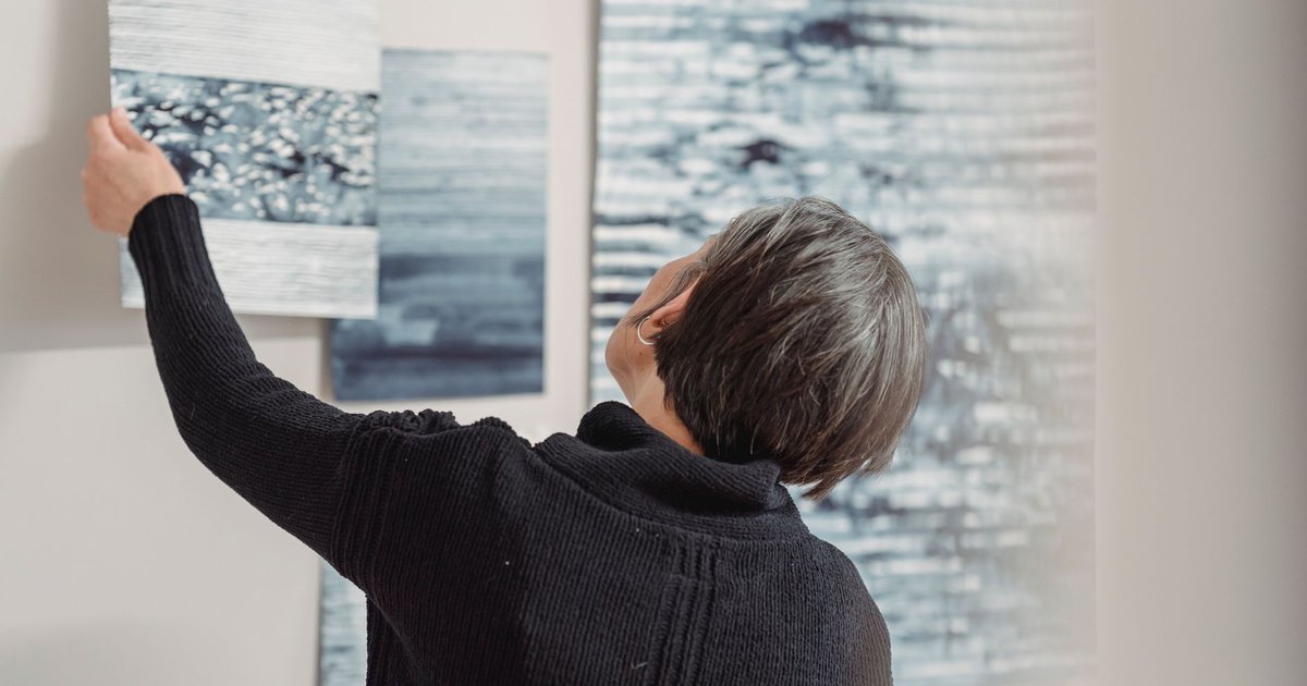 Une personne observe une peinture abstraite accrochée au mur d'une galerie