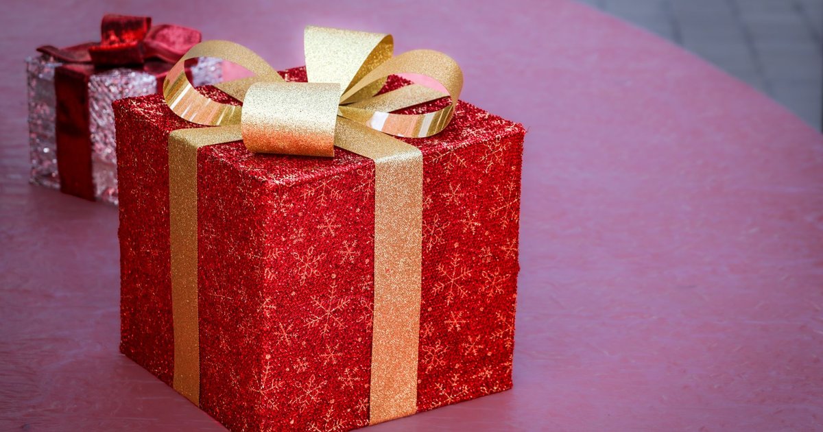 Paquet cadeau rouge pailleté noué d'un ruban doré, posé à côté d'un second présent argenté
