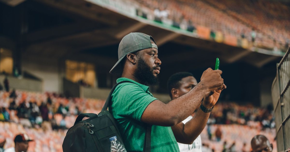 Un supporter filme un événement sportif avec son smartphone dans les tribunes